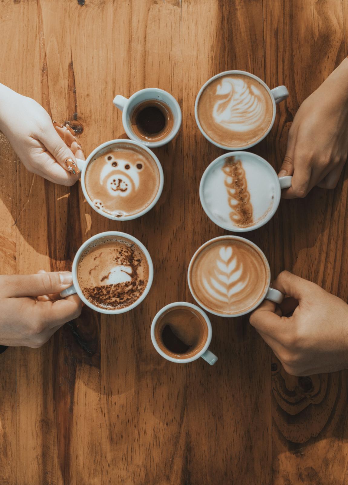 People sitting around a table together with drinks and food at a Love Meets Coffee gathering.