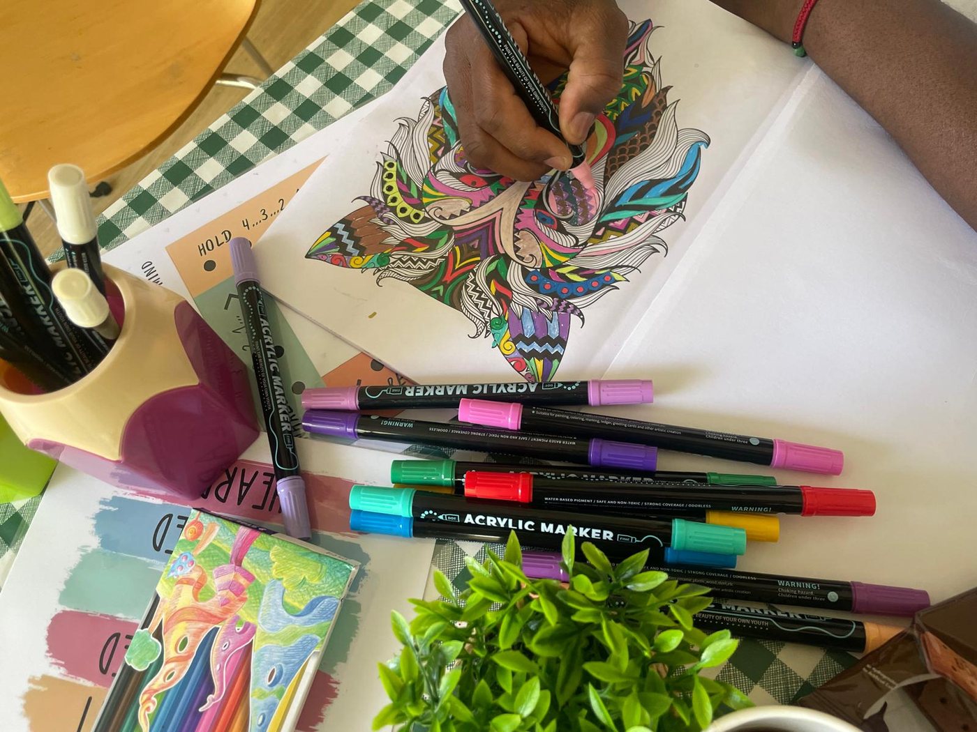 Someone colouring a detailed drawing with bright acrylic markers.